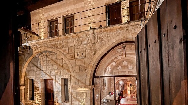 An interior with stone arches, a staircase, and a view into a room with a red carpet.
