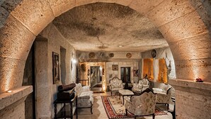 An arched stone interior with a fireplace, seating area, and a view into another room.