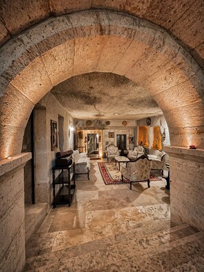 An arched stone interior with a fireplace, seating area, and a view into another room.