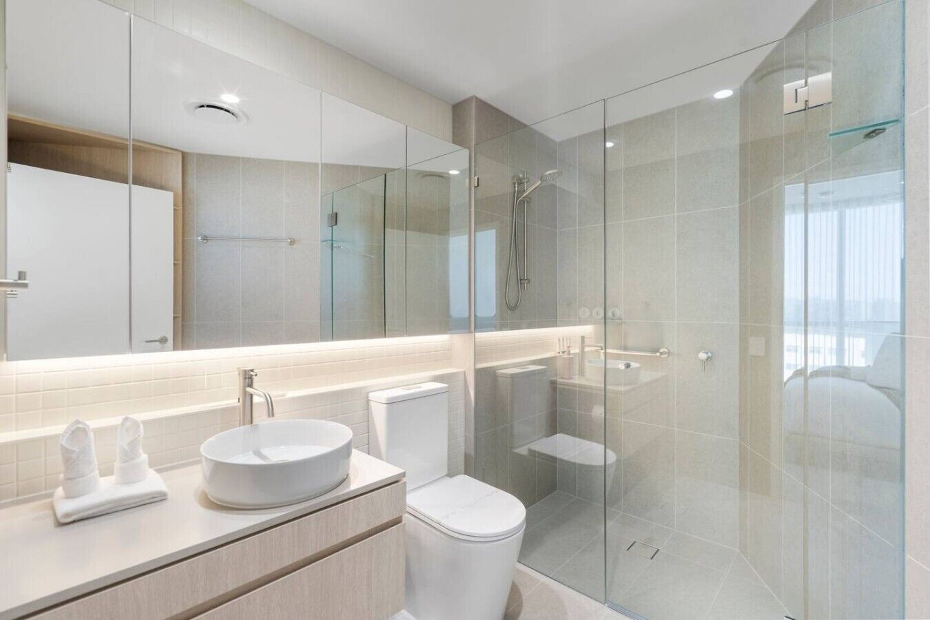 A modern bathroom with a glass-enclosed shower, a round sink, and a toilet.