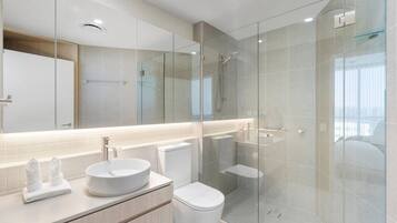 A modern bathroom with a glass-enclosed shower, a round sink, and a toilet.