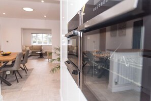 Eine moderne Küche mit einem großen Backofen, ein Essbereich mit Tisch und Stühlen sowie ein Fenster mit Blick nach draußen.