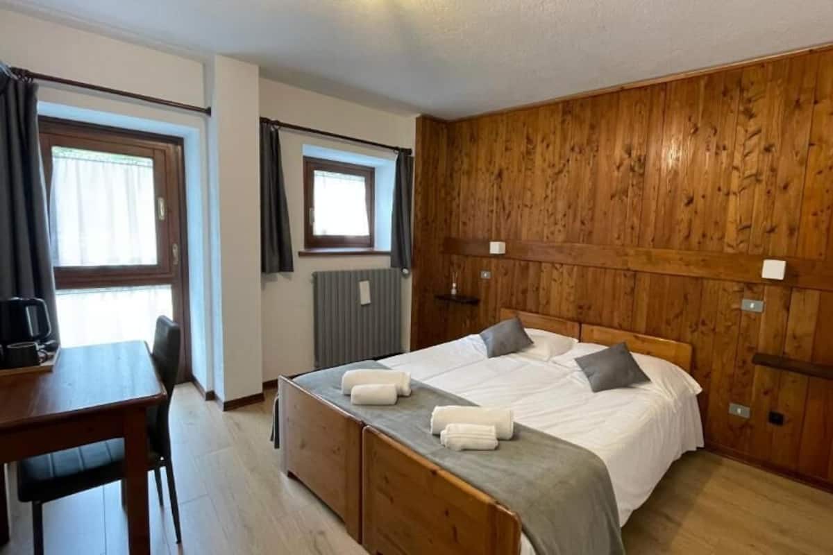 Une chambre à coucher avec une tête de lit en bois, un lit avec une literie blanche, une table de chevet et une chaise.