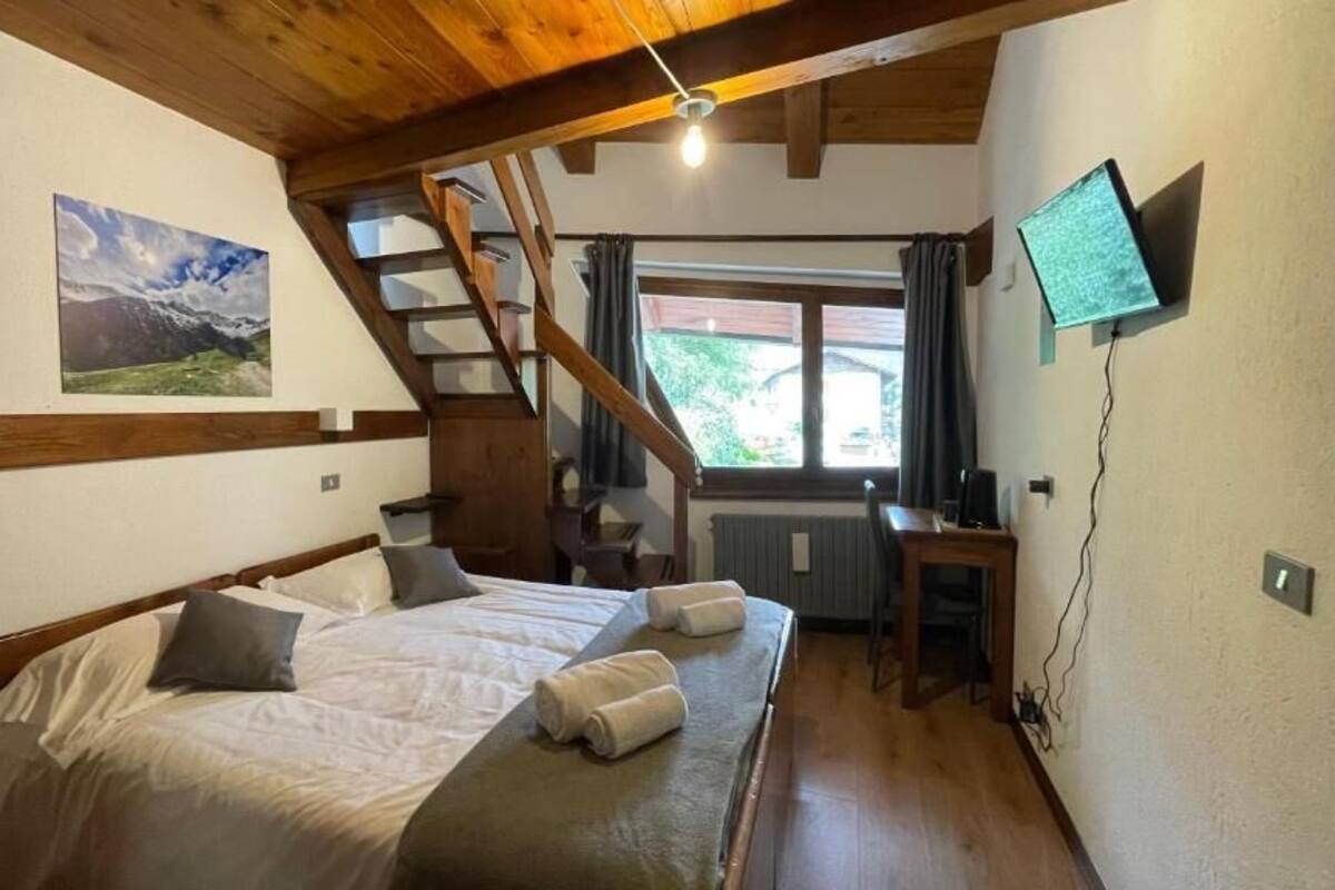 Une chambre Ă coucher avec un lit, un bureau, une tĂ©lĂ©vision, une fenĂȘtre et un escalier.