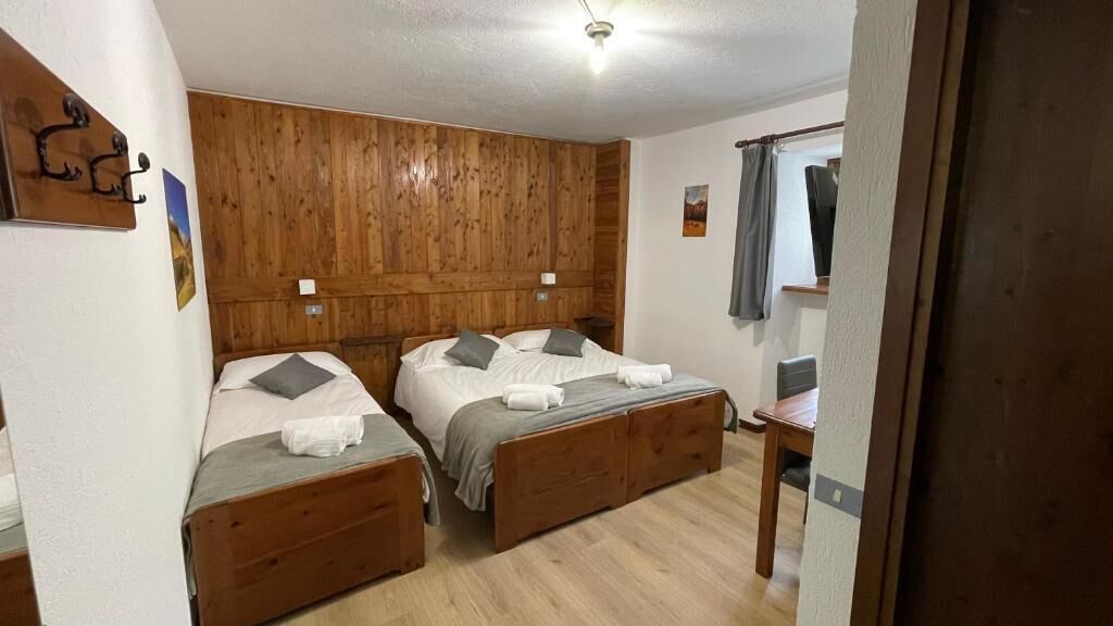 Een kamer met twee houten bedden, een tafeltje en een spiegel.