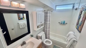 A bathroom with a sink, toilet, bathtub, and a shower curtain. - Delightful condo with AC in vibrant Honolulu perfect for your stay (Honolulu)