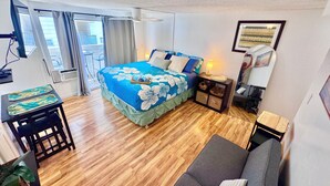 A hotel room with a bed, a desk, a chair, a sofa, a TV, and a window with curtains. - Delightful condo with AC in vibrant Honolulu perfect for your stay (Honolulu)