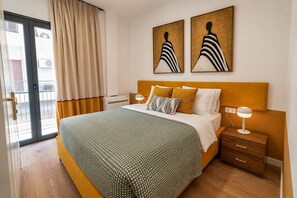 Ein Schlafzimmer mit einem Bett, Nachttischen, einer Lampe und Kunstwerken an der Wand.