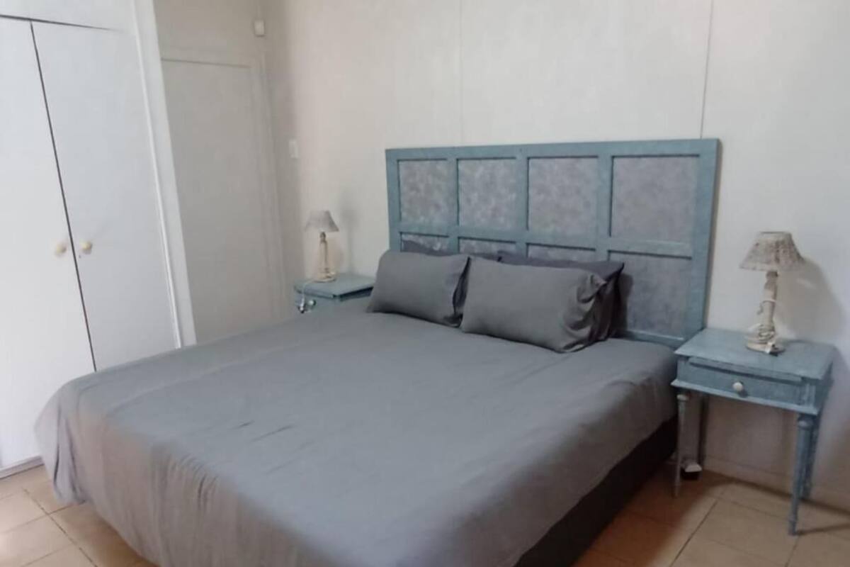 Un dormitorio con una cama, mesitas de noche y un armario.
