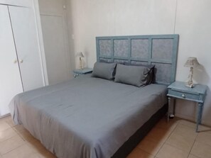 Un dormitorio con una cama, mesitas de noche y un armario.