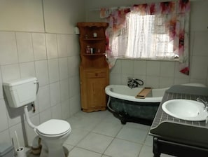 A bathroom with a toilet, a wooden cabinet, a bathtub, and a sink.