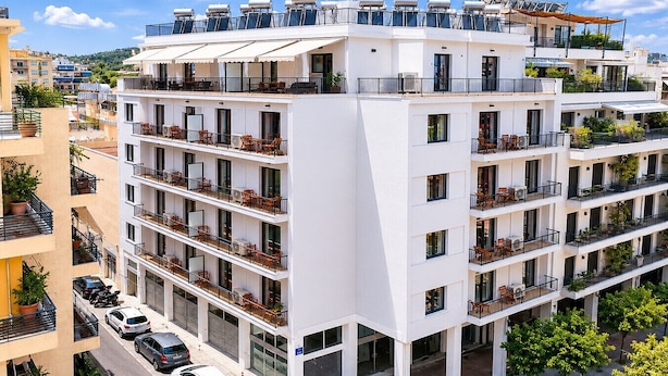A multi-story hotel with balconies, a rooftop terrace, and a parking area. - LIV - Upscale Athenian Apartment 1C (Athens)