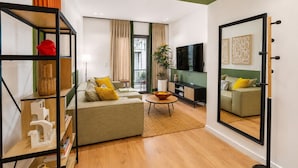 A modern living room with a sofa, a coffee table, a TV, and a bookshelf. - LIV - Upscale Athenian Apartment 1C (Athens)