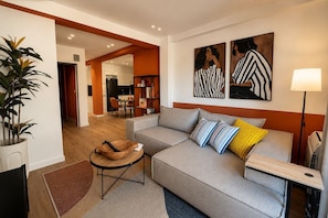 Ein modernes Wohnzimmer mit einer Couch, einem Beistelltisch, einer Stehlampe und Bildern an der Wand.