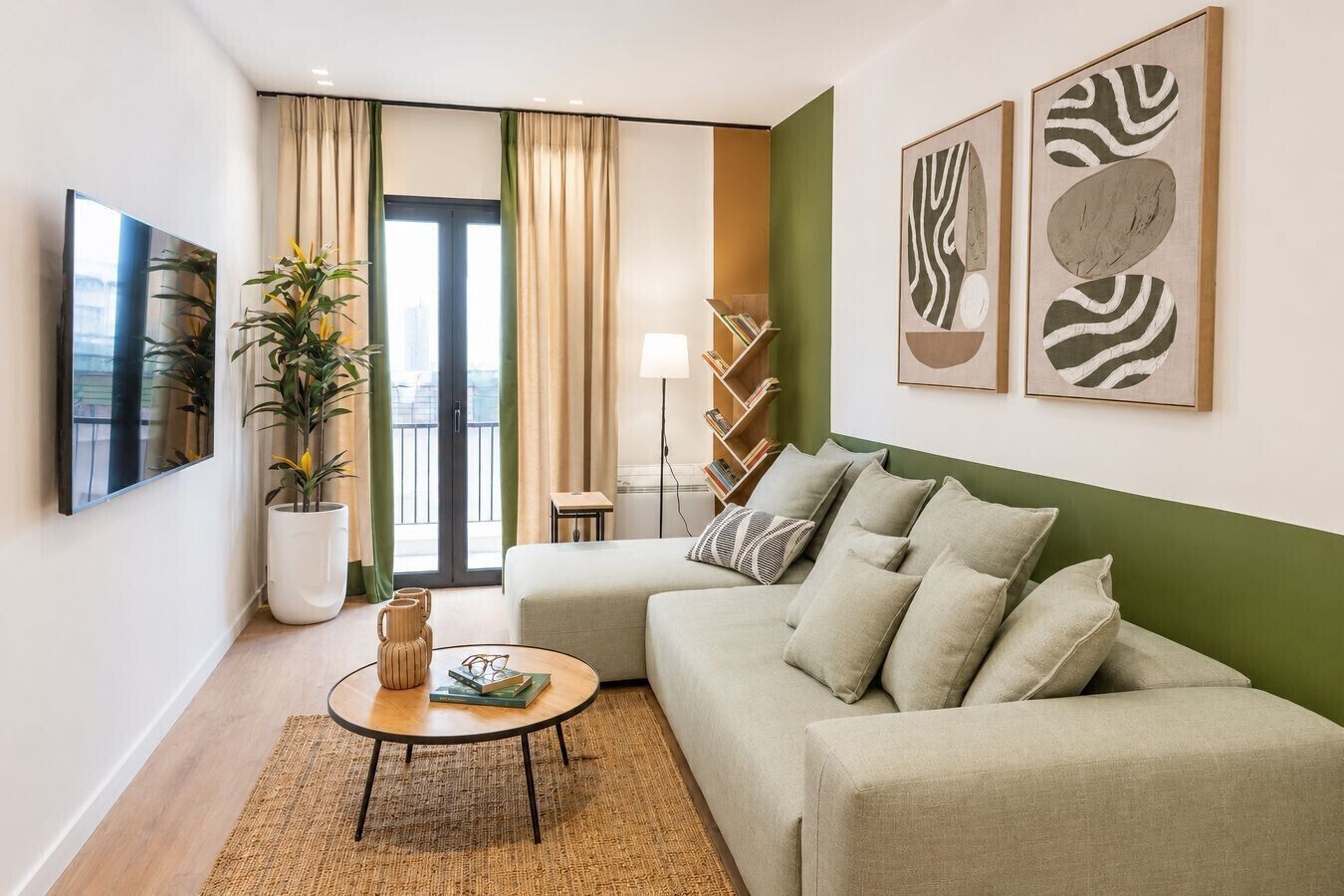 A living room with a sofa, a coffee table, a bookshelf, and a large window with curtains.