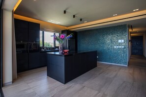 Una cocina moderna con una isla central, muebles oscuros y un jarrón decorativo con flores.
