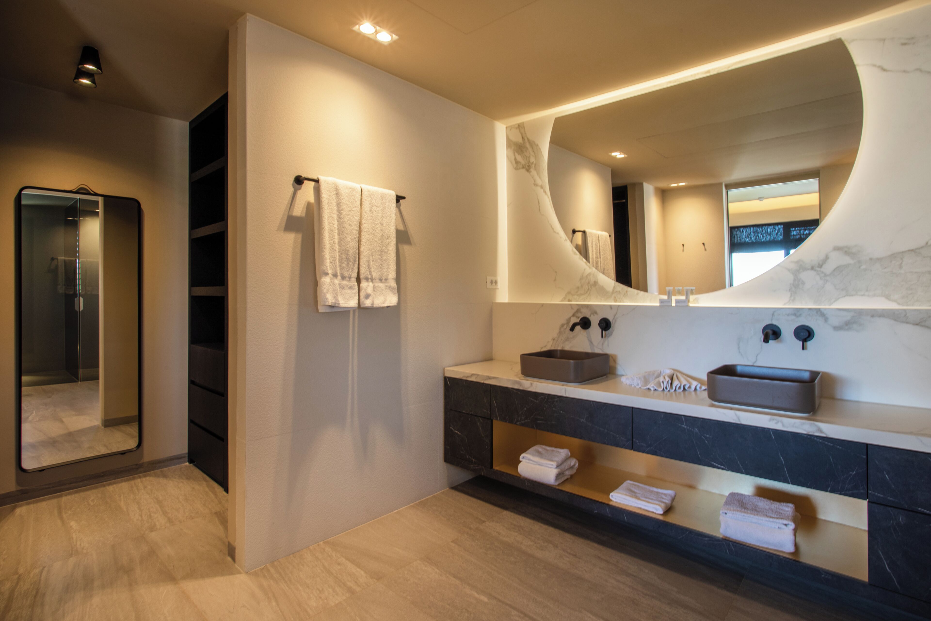A modern bathroom with a large mirror, a sink with a marble countertop, and a towel rack.