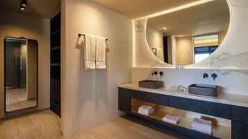 A modern bathroom with a large mirror, a sink with a marble countertop, and a towel rack.