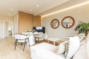 A modern living room with a dining area, white furniture, and a flat-screen TV. - Recanto do Sol by Atlantic Holiday (Caniçal)
