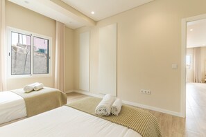 A hotel room with two beds, a large window, a mirror, and a view of the outside.
