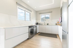 A modern kitchen with built-in appliances, a washing machine, and a view of the outdoors. - Recanto do Sol by Atlantic Holiday (Caniçal)