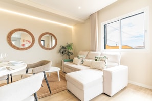A modern living room with a sofa, chairs, a dining table, and two wall-mounted mirrors. - Recanto do Sol by Atlantic Holiday (Caniçal)