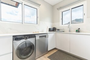 A compact kitchen with a washing machine, dishwasher, and a coffee maker.