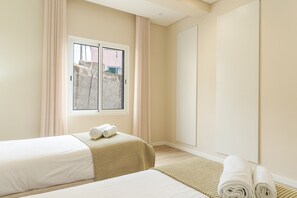 A hotel room with two beds, a window with a view of buildings, and a large mirror. - Recanto do Sol by Atlantic Holiday (Caniçal)