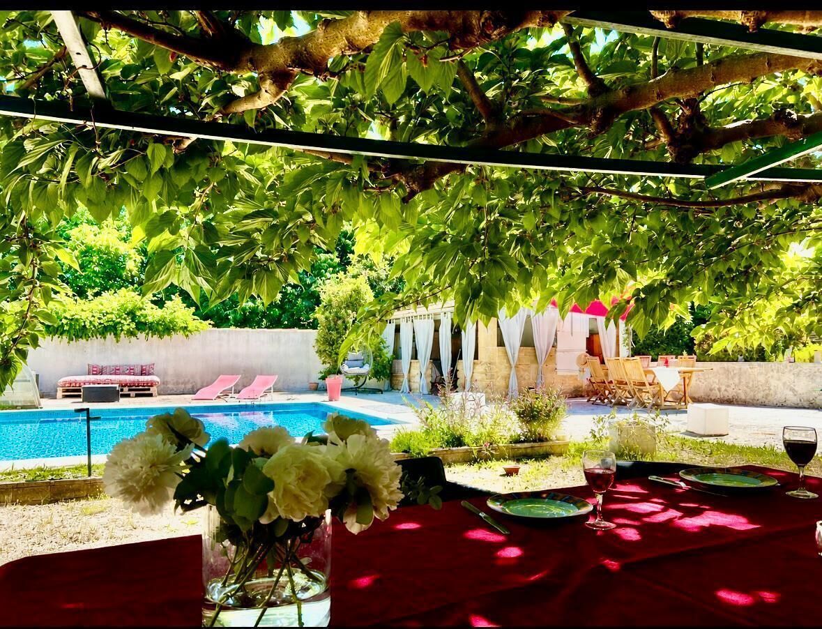 Un área junto a la piscina con mesa lista para comer, una silla y un arreglo floral.