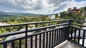 Un balcone con vista su una zona residenziale, tra case e vegetazione.