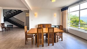Zona pranzo con tavolo e sedie in legno, una scala e un'ampia finestra con vista.