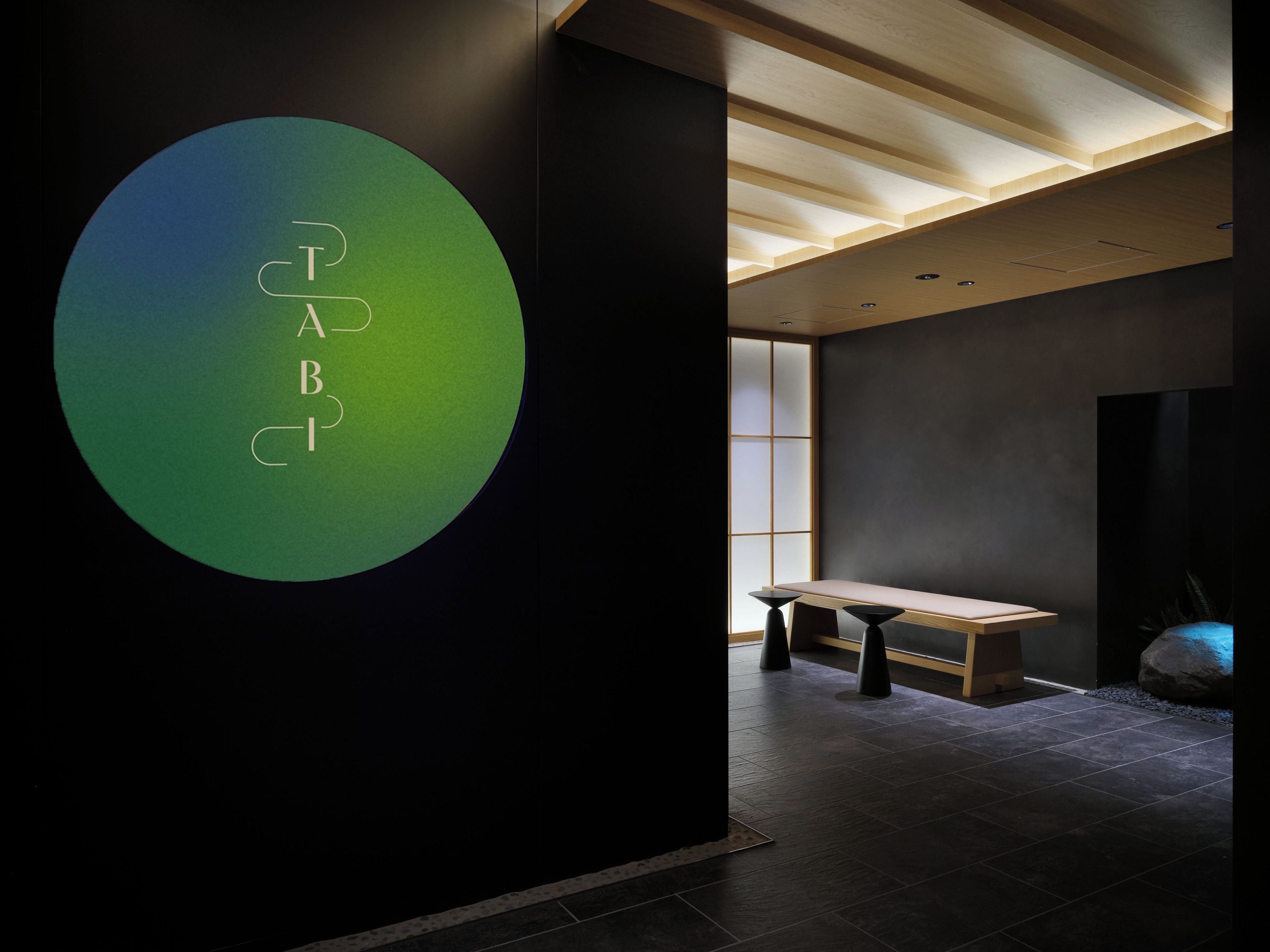 Ein modernes Interieur mit einem runden Logo, einer hölzernen Bank und einem Fliesenboden.