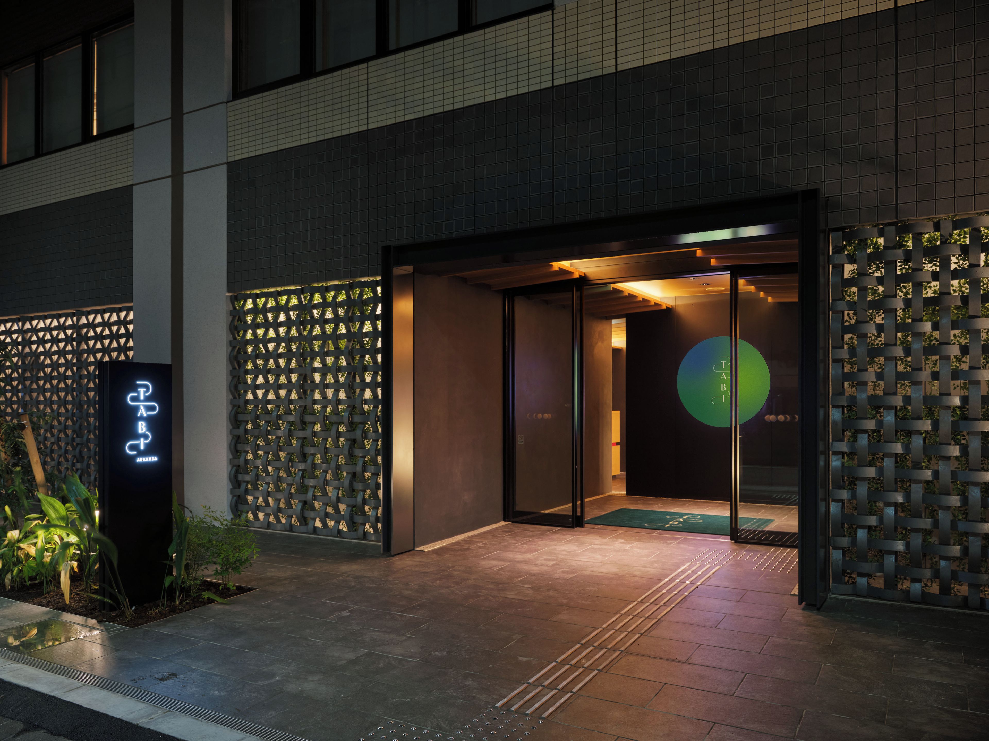 A modern building entrance with a glass door, a metal fence, and a signboard.