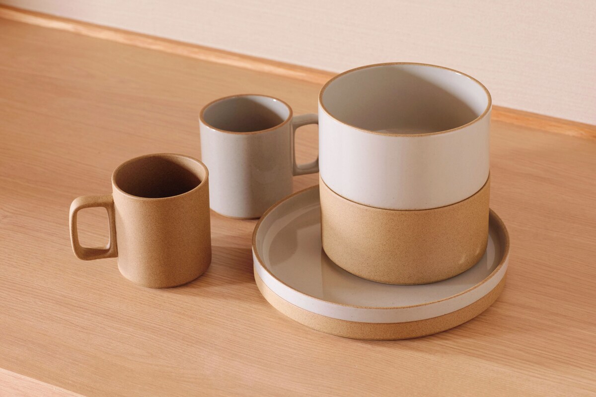 A set of three ceramic mugs on a wooden table.
