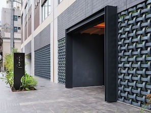 A modern building facade with a black metal gate, a clear sky, and a paved walkway. - TABI ASAKUSA (Tokyo)