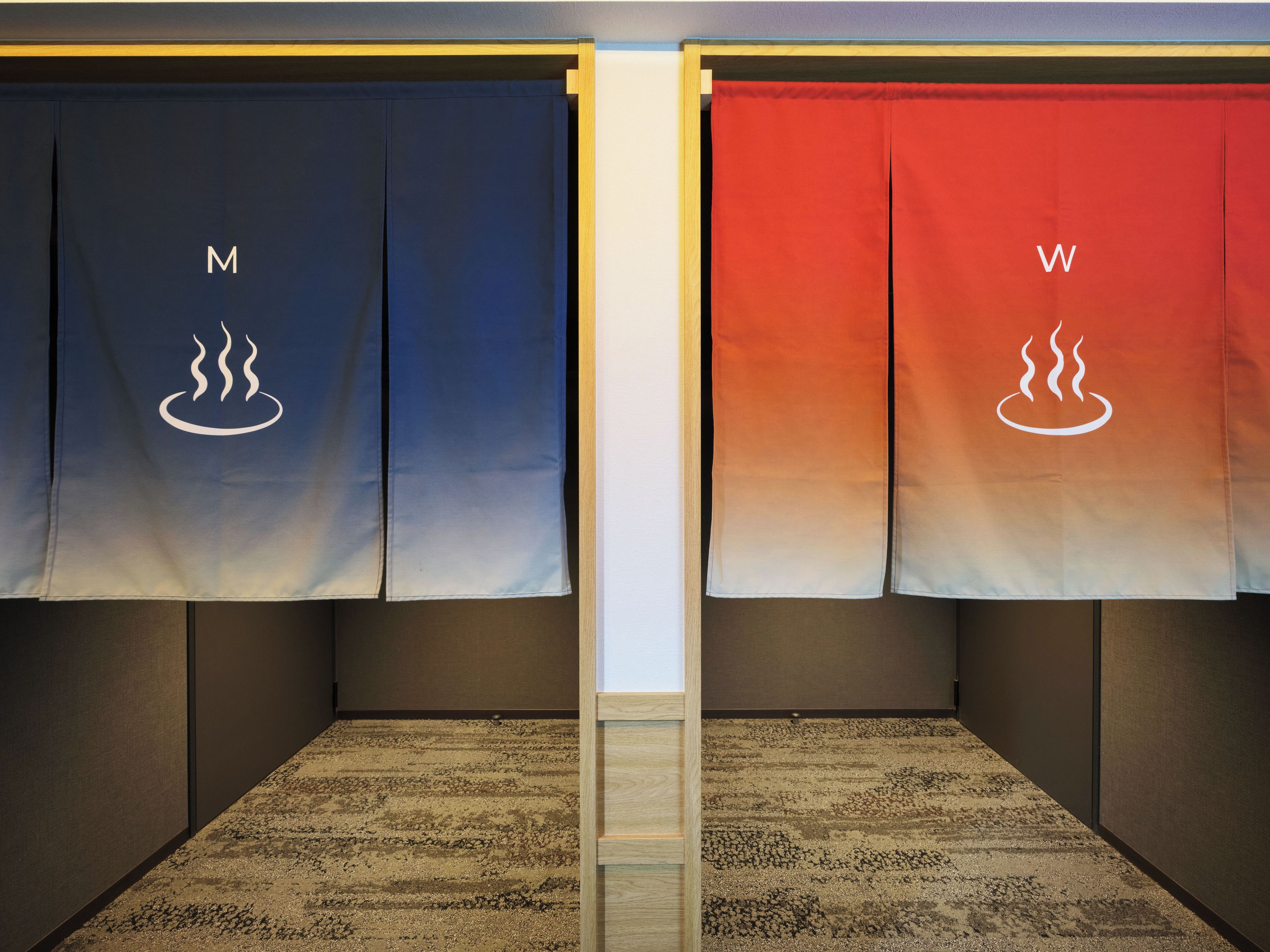 A room with two towels hanging on a wall, one labeled 'M' and the other 'W'.