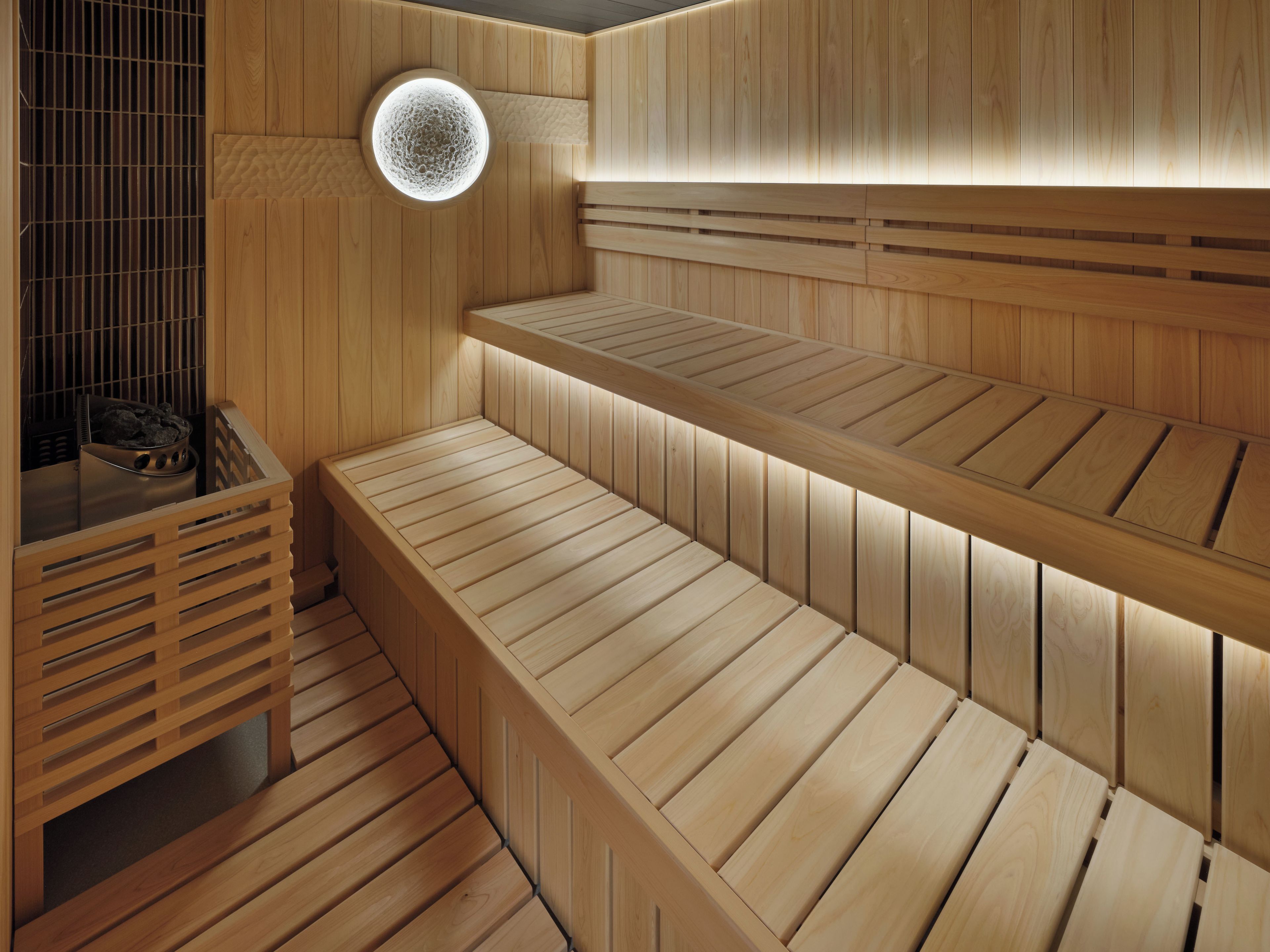 A sauna with wooden benches and a circular light fixture.