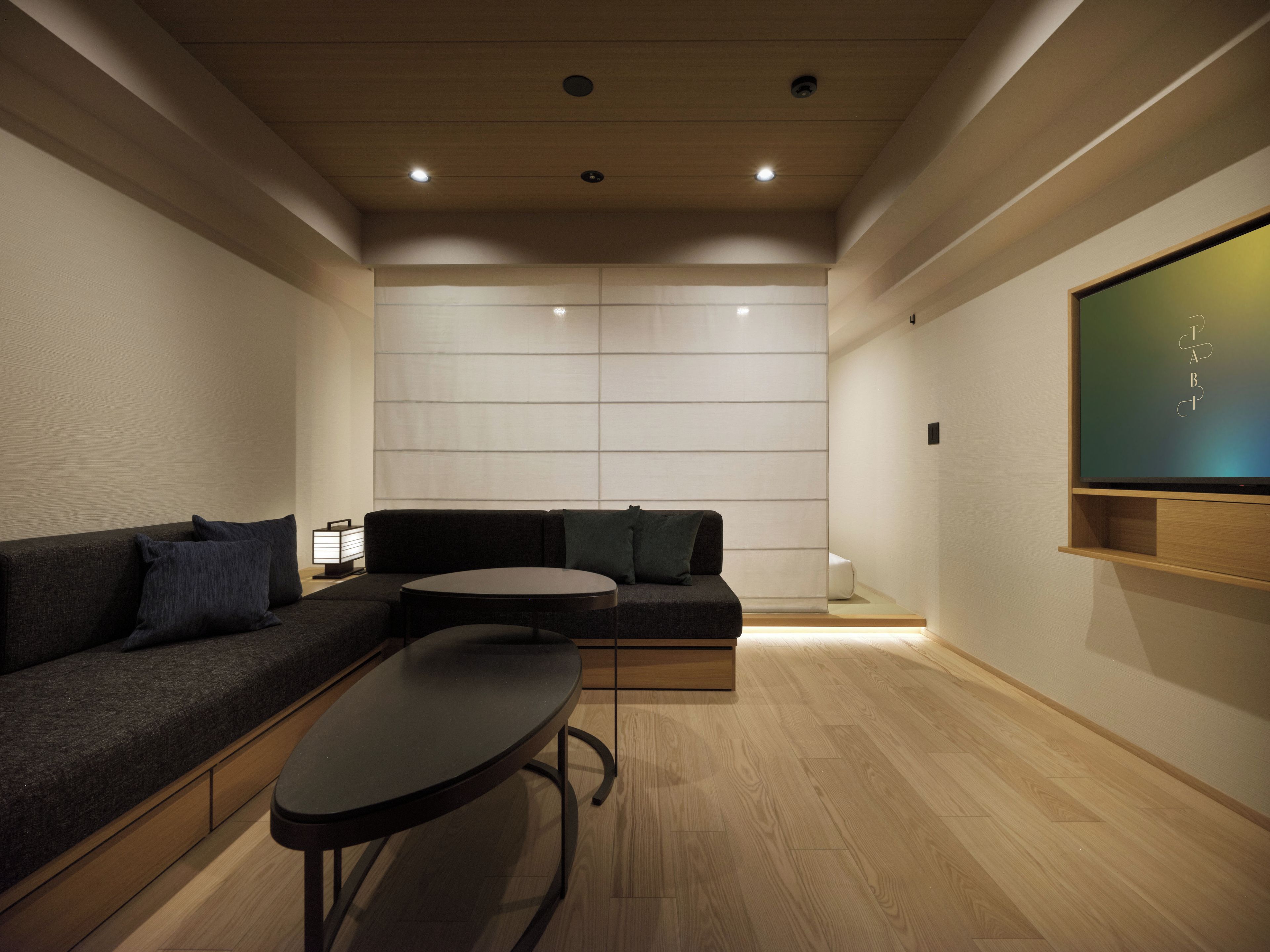 A modern living room with a sectional sofa, a round coffee table, and a flat-screen TV mounted on the wall.