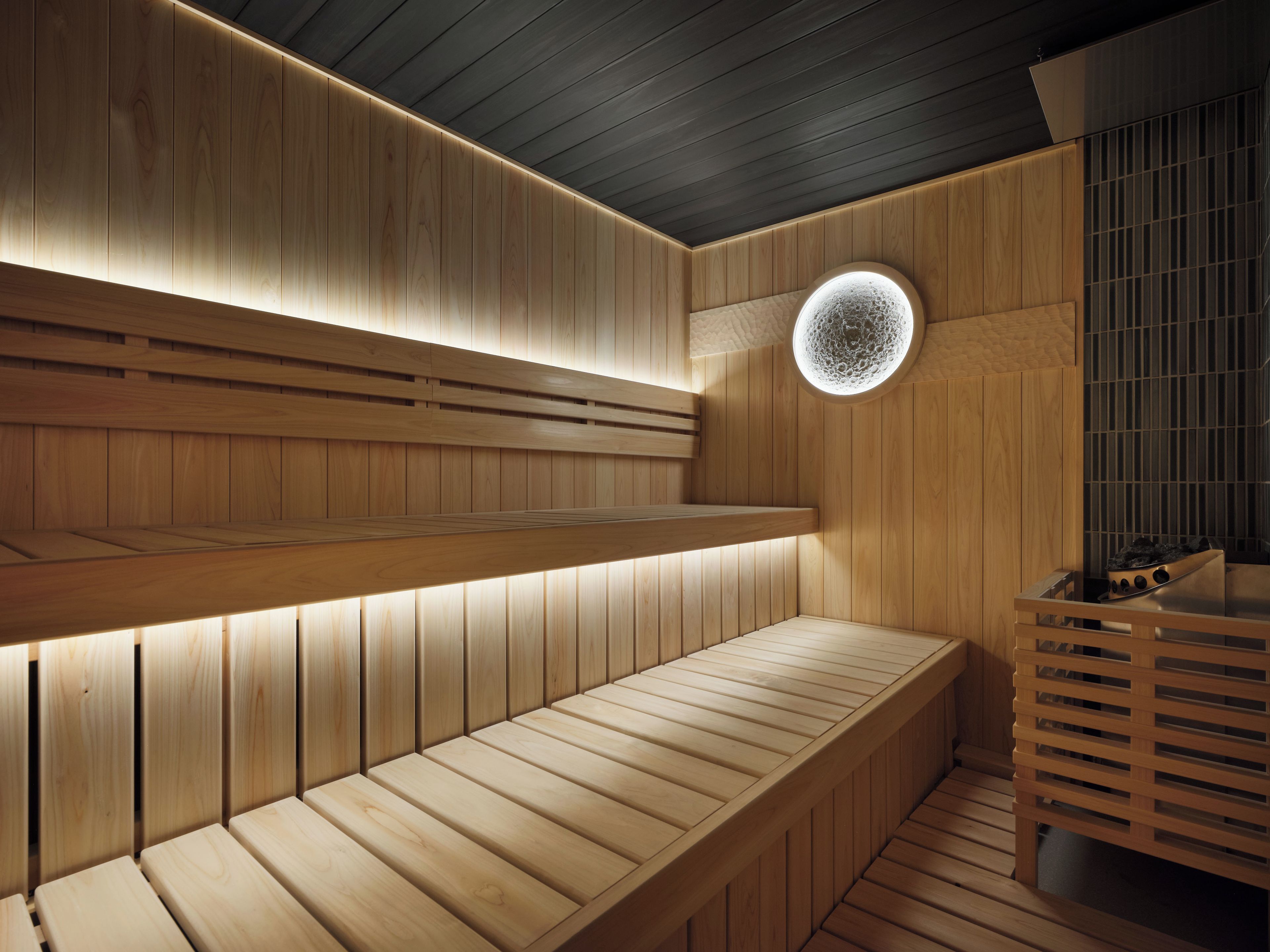 A sauna with wooden benches and a circular skylight.