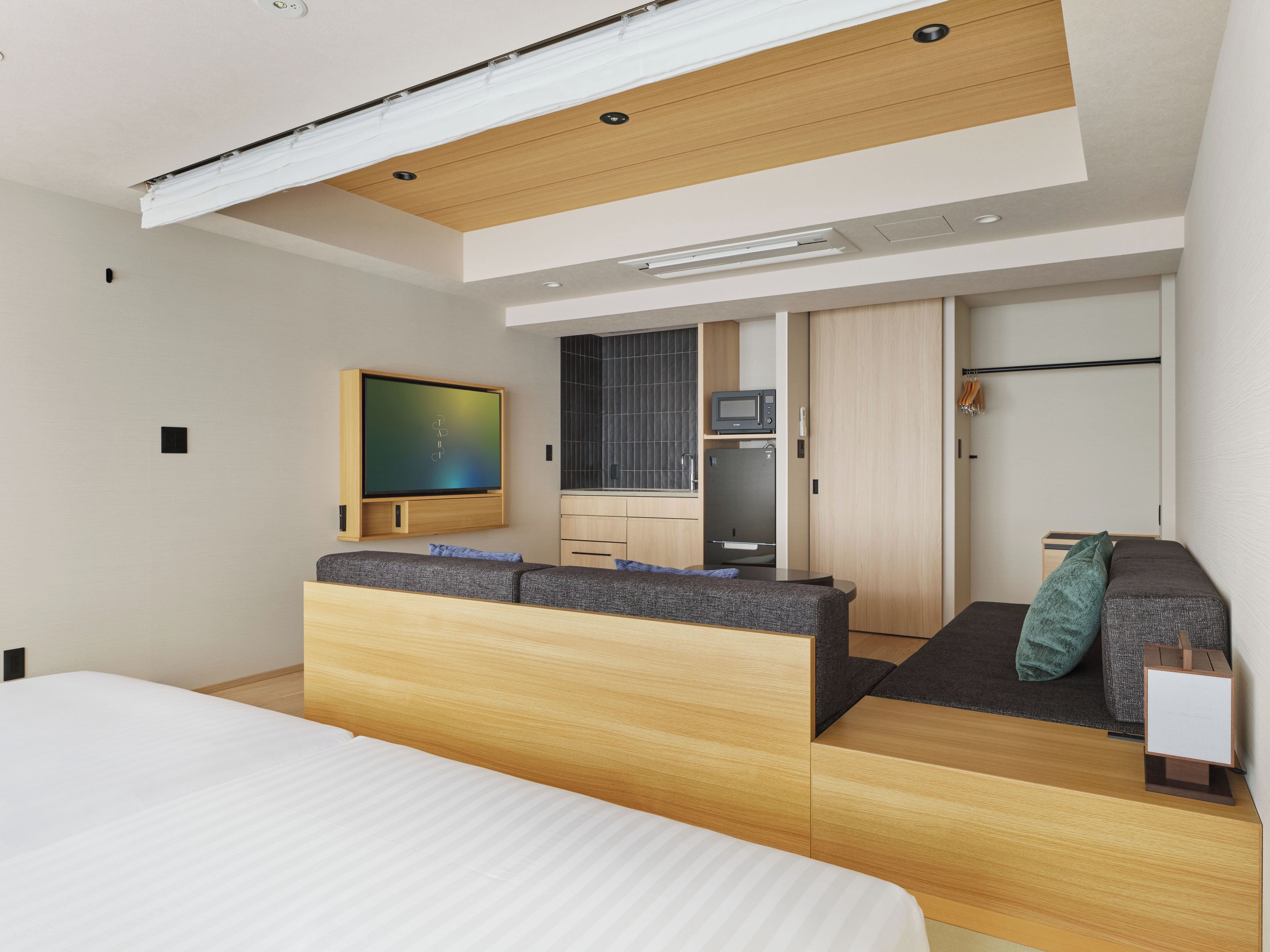 Una habitación de hotel moderna con cama, sofá, televisión, microondas y refrigerador.