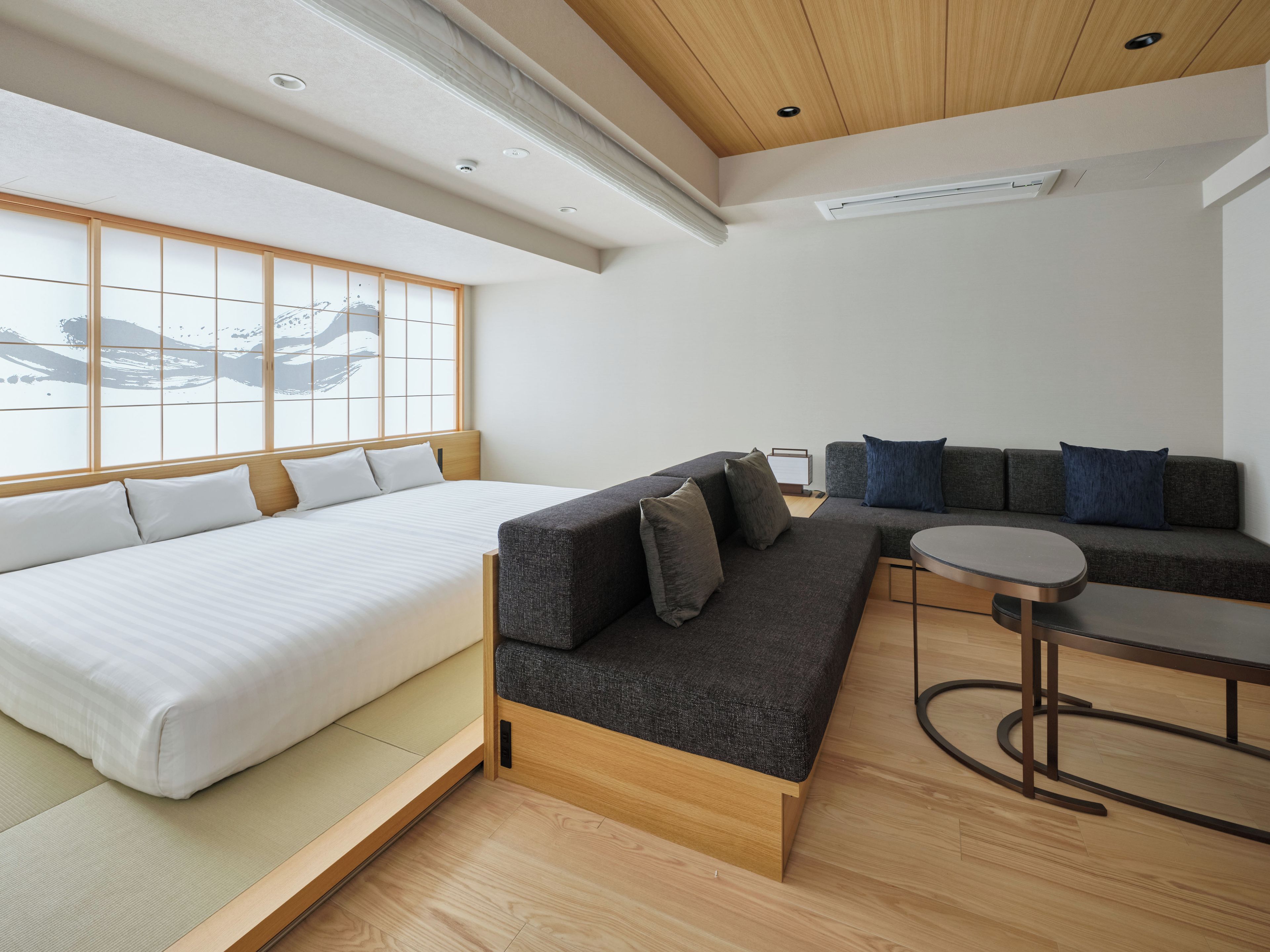 A modern room with a bed, sofa, and a small table.