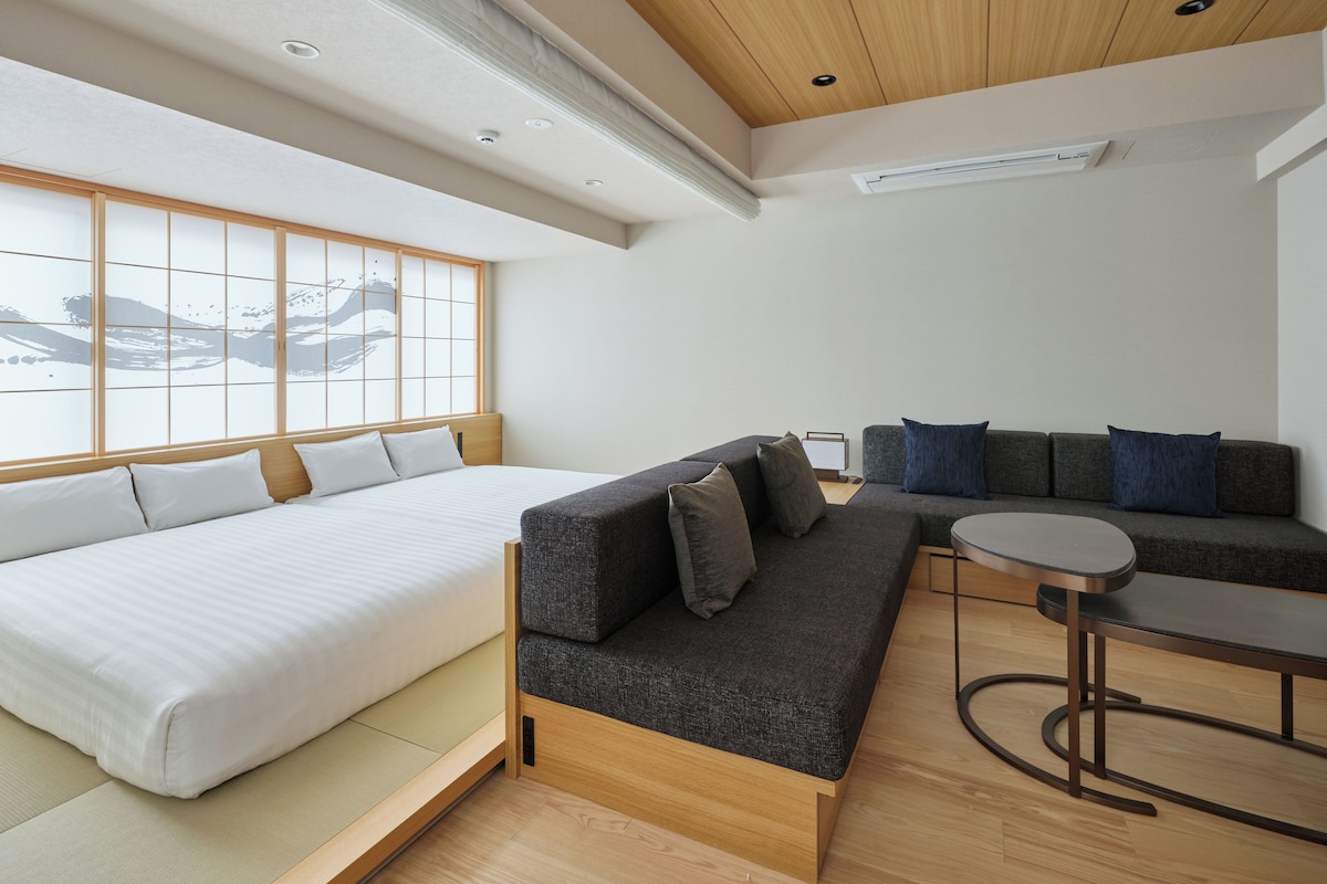 A modern room with a bed, sofa, and a small table.