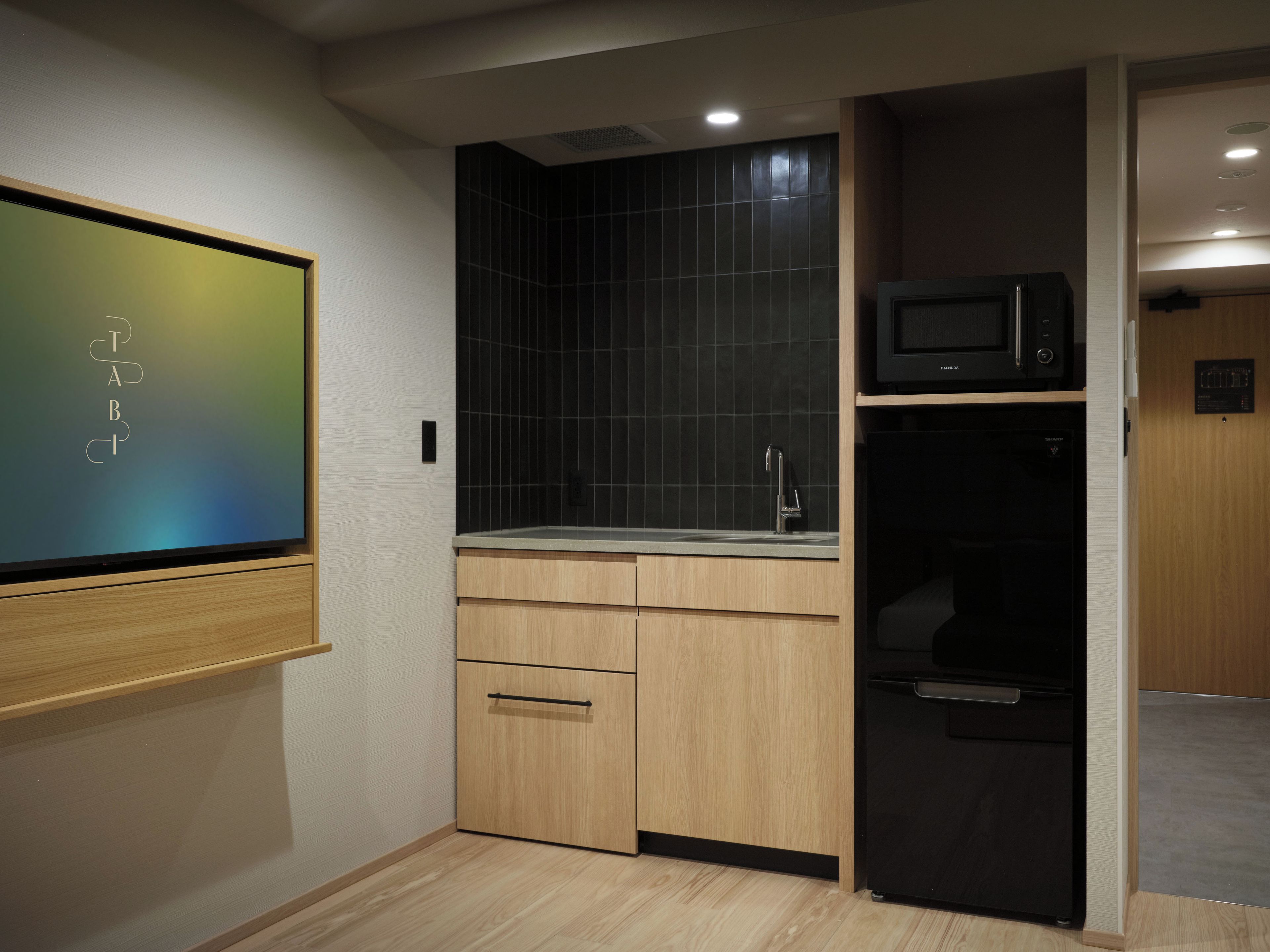A compact kitchen with a microwave, sink, and wooden cabinets.