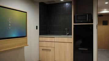 A compact kitchen with a microwave, sink, and wooden cabinets.