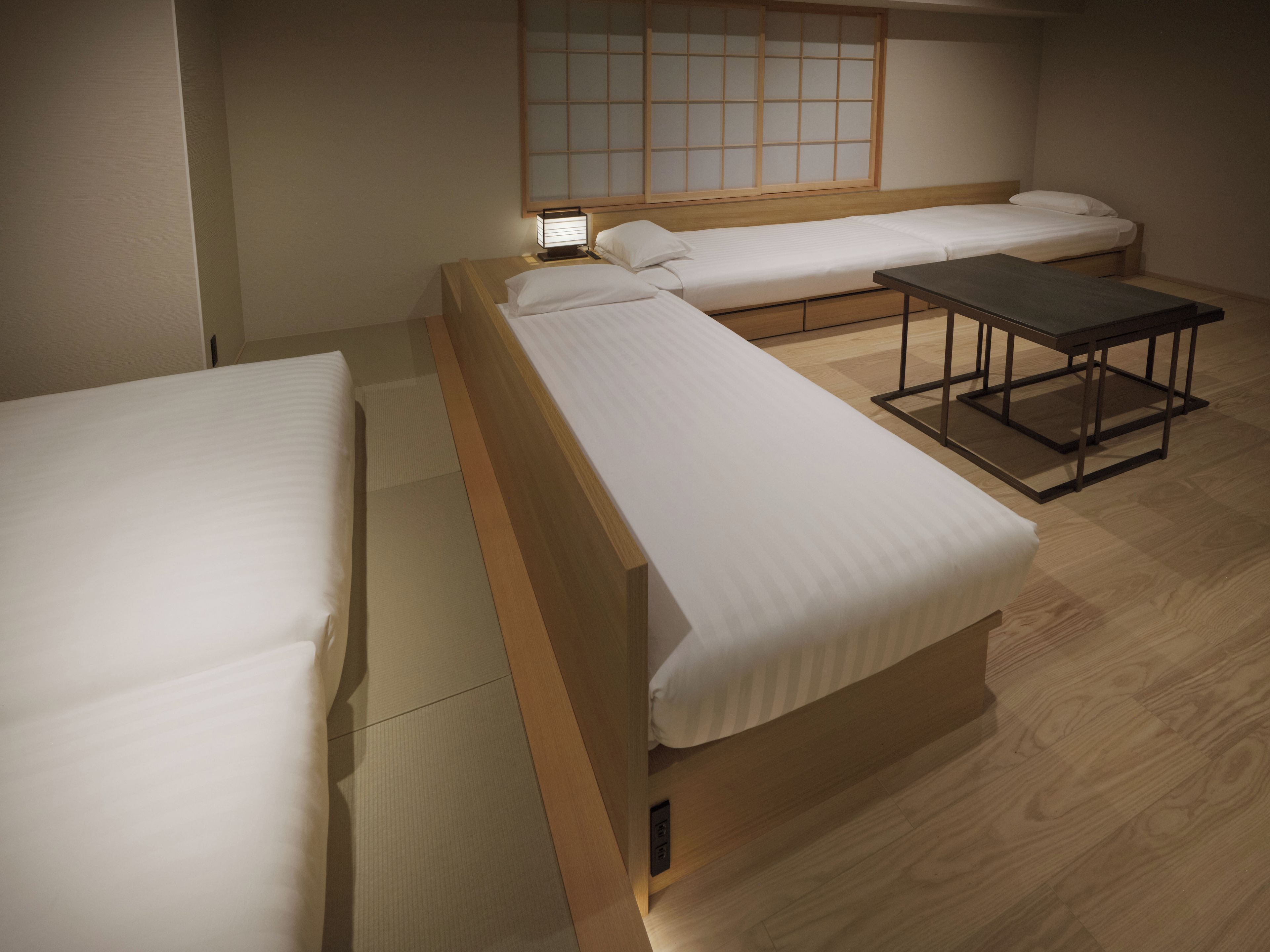Een hotelkamer met twee eenpersoonsbedden, een tafeltje en een schuifdeur in shoji-stijl.