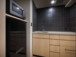 A compact kitchen with a built-in microwave, a sink, and wooden cabinets.