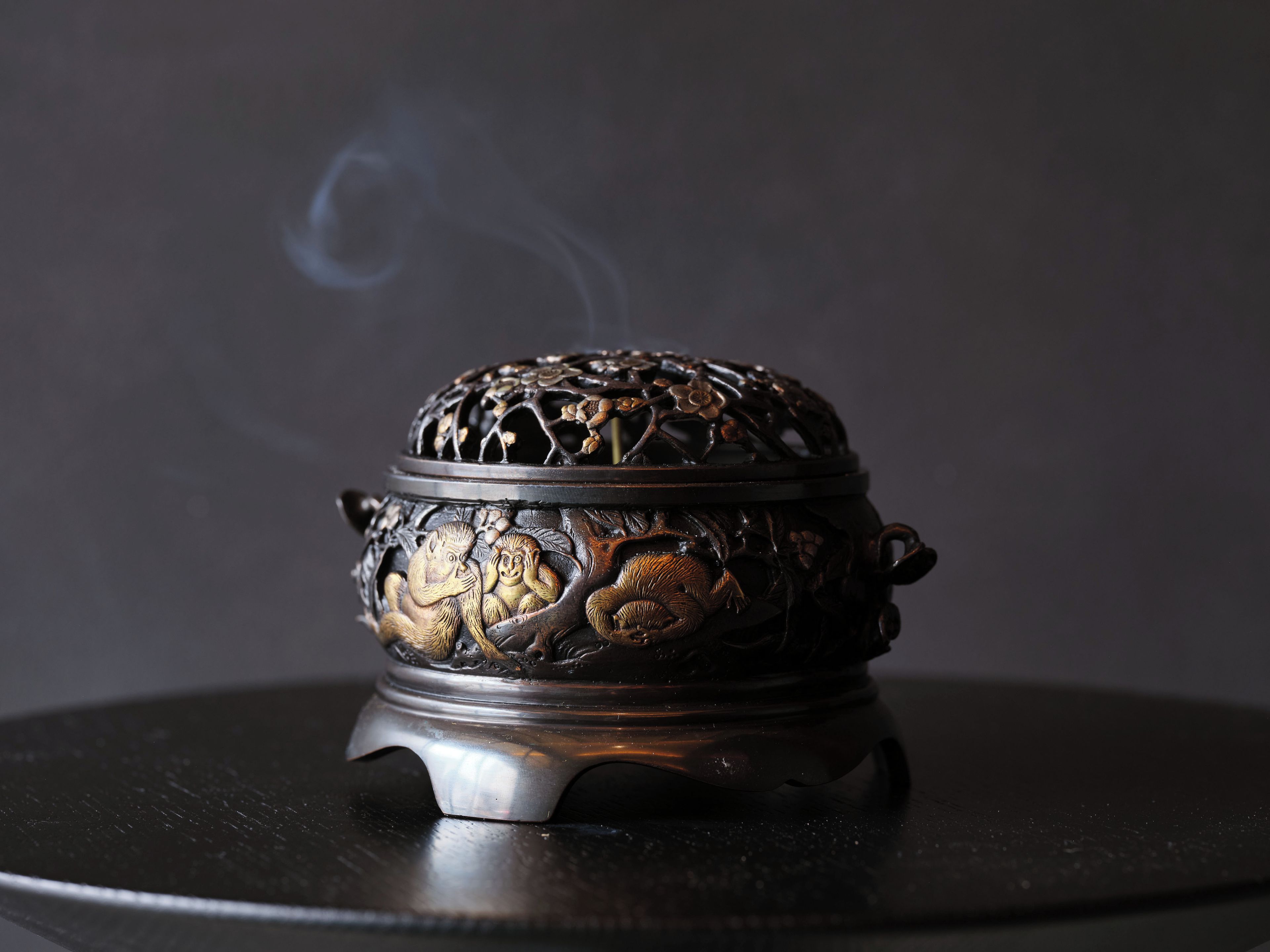 A traditional incense burner with intricate carvings and smoke rising from it.