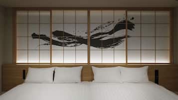 A hotel room with a large bed, two pillows, and a wall with a black abstract design.