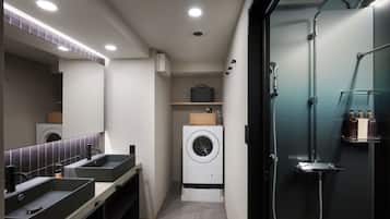 A modern bathroom with dual sinks, a large mirror, a washing machine, and a shower enclosure.