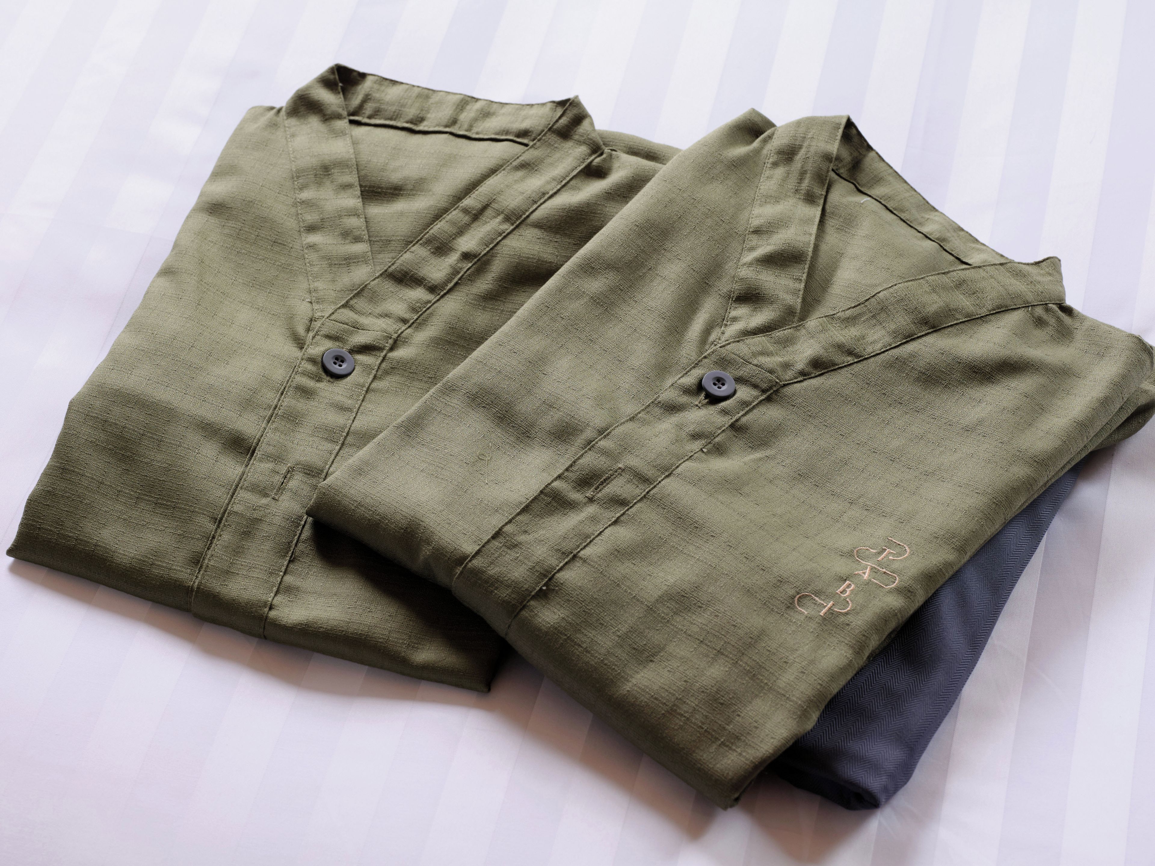 Two folded shirts with buttons and a small embroidered detail on one.